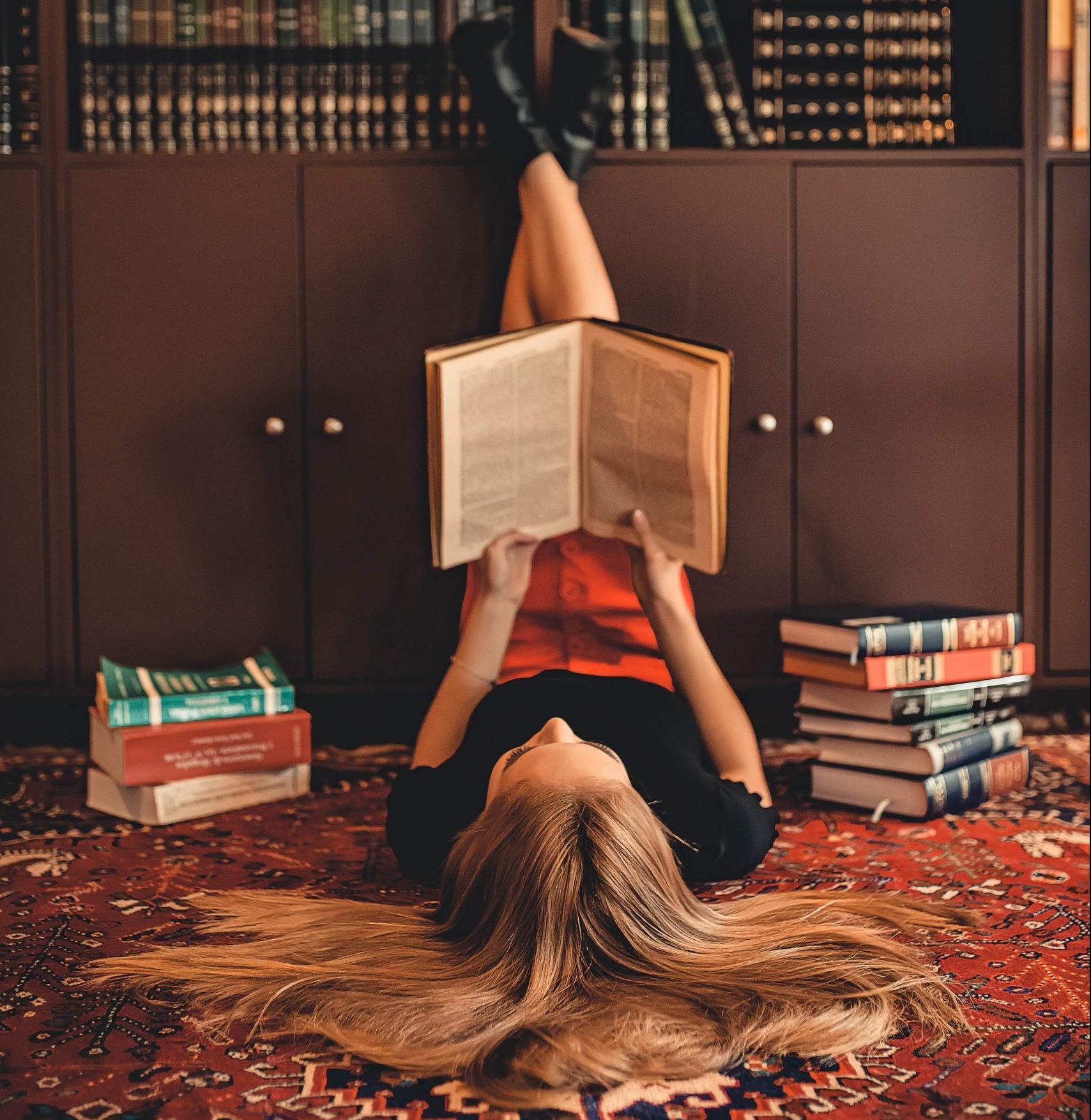 woman-lying-on-area-rug-reading-books-2899918